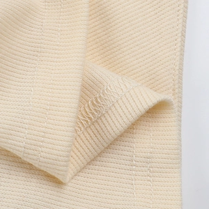 Makroaufnahme der Rippstrickstruktur und der präzisen Nähte des beigen Neckholder-Tops