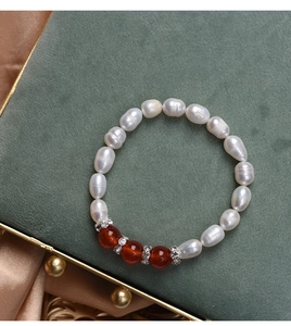 Detail of freshwater pearl and red agate beaded bracelet with diamond spacers on velvet