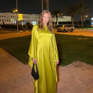 Detailed view of yellow satin maxi dress with batwing sleeves in a night street scene