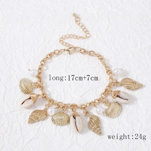 Detail of gold shell and pearl bracelet with nautical charms on textured background