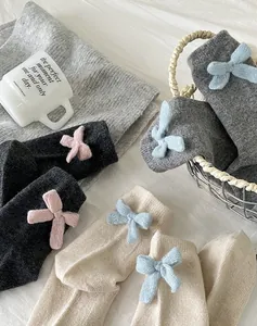 Close-up of knit wool socks featuring decorative bows in multiple color combinations