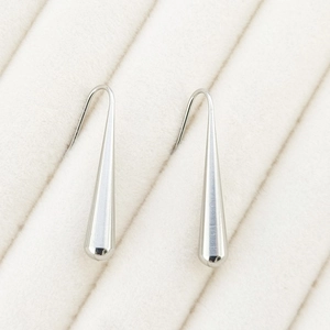 Macro detail of polished silver teardrop earrings with elegant curved hooks