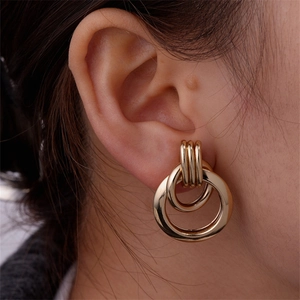 Detail view of golden multi-layer intertwined hoop earrings worn by a model