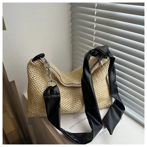 Detail of woven straw texture with black faux leather strap and silver chain accent