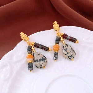 Close-up of vintage teardrop stone beaded tassel earrings on a decorative ceramic dish