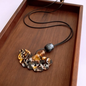 Vue détaillée du collier pendentif nuage ruyi évidé sur un plateau en bois