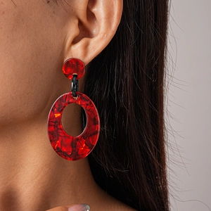 Detail of red hollow acrylic drop earrings featuring a retro geometric oval design