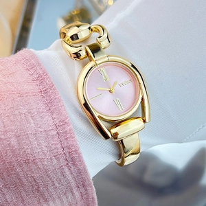 Close-up of golden bracelet watch with pink dial and Roman numerals on woman wrist