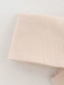 Detailed macro view showing the coarse beige woven fabric texture and refined material quality