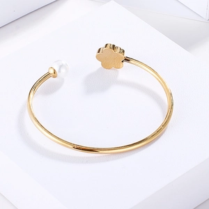 Detailed close-up of a gold-plated flower ring with a white pearl on a white stand