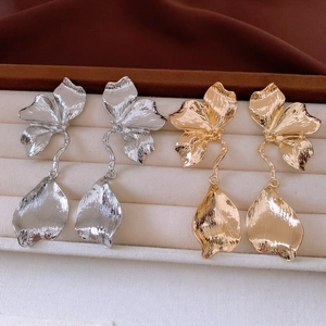 Vue détaillée de grandes boucles d'oreilles fleurs en or et argent avec texture brossée