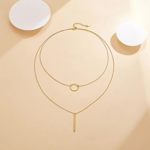 Detail of a double-layer gold geometric necklace with circular and vertical bar pendants