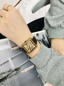 Detalle de reloj vintage cuadrado con números grandes y correa de cuero marrón