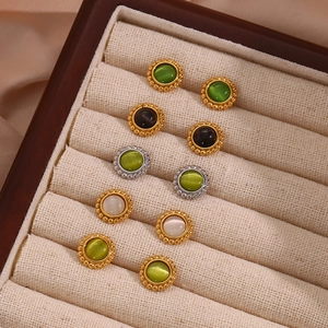 Close-up of vintage beaded stud earrings with colorful cat eye stones in a wooden box