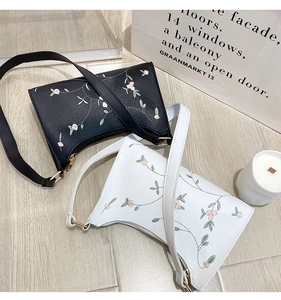 Flat lay of black and white women's shoulder bags with colorful floral embroidery