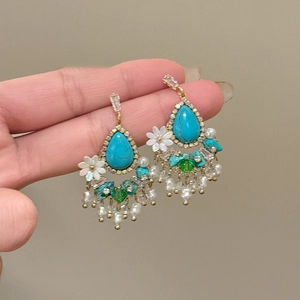 Detail of bohemian drop earrings with turquoise, white floral motifs and pearl tassels