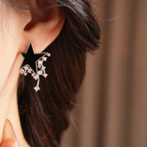 Close-up of model wearing black star zircon earrings with rose gold tassel detail