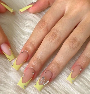 Macro detail of French pale yellow square nails with silver rhinestone butterfly accent