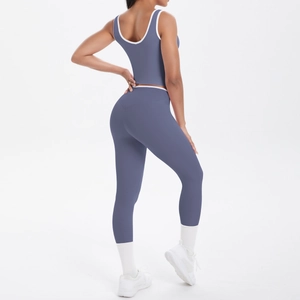 Detail of high-waist yoga pants and sports bra featuring white contrast trim on grey-blue fabric