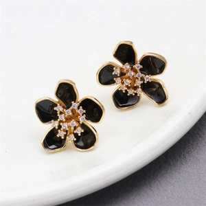 Detail shot of black enamel flower earrings with gold edges and micro-set cubic zirconia