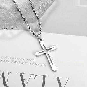 Macro shot of silver stainless steel cross pendant with hollow star detail on box chain