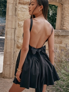 Detail of a black backless dress featuring a large decorative bow and elegant A-line cut