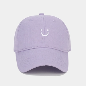 Close-up of a light purple cotton baseball cap featuring a white embroidered smiley face