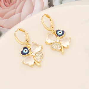 Macro detail of gold four-leaf clover earrings with zircon petals and evil eye pendant