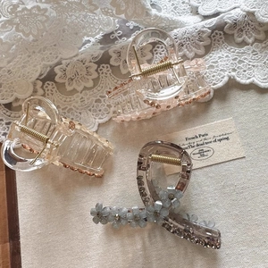 Detail of elegant crystal flower hair claws with golden springs on lace and linen background