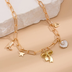 Detailed close-up of golden chain necklace with bow, star, and shell pearl pendants