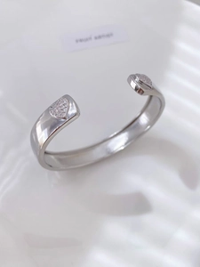 Detailed view of silver open cuff bracelet with zircon-encrusted heart shaped ends