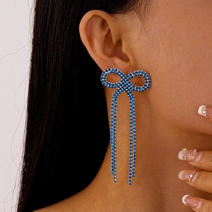 Vue détaillée des boucles d'oreilles argentées avec nœud en cristal bleu et franges