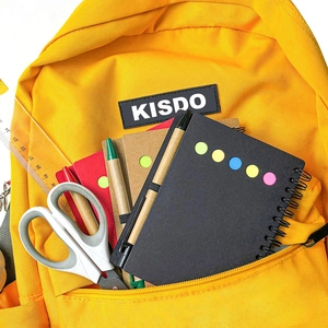 Gelber Canvas-Rucksack mit Vordertasche gefüllt mit Notizbuch, Stiften, Lineal und Schere