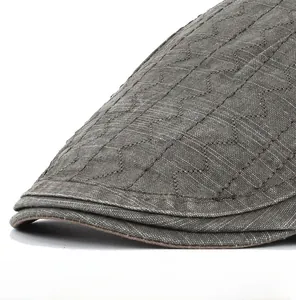 Macro detail of men's cotton flat cap showing grey textured fabric and wave stitching