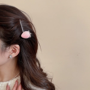Detail shot of a pink velvet strawberry hair clip worn by a model in soft lighting