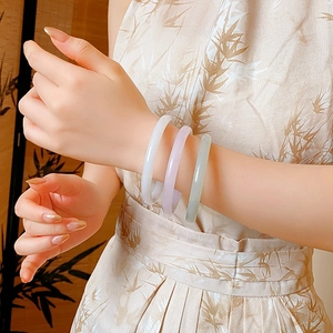 Close-up of three elegant jade bangles in purple, green and white on a model's wrist
