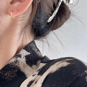 Close-up of minimalist gold curved ear stud showing polished texture and geometric shape