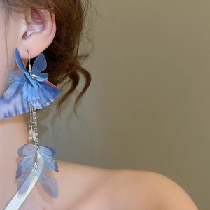 Detail of blue tulle butterfly earrings with silver fringe and teardrop pendant on ear