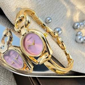 Detailed macro view of the gold alloy horseshoe case and pink oval dial on woman's watch