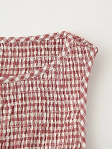 Detailed view of red gingham plaid dress with smocked elastic texture and round neckline
