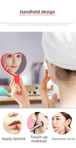 Close-up of heart-shaped handheld mirror with ergonomic red handle for precise makeup