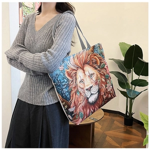 Detail of 3D lion embroidery on canvas tote bag with striped black and white handle