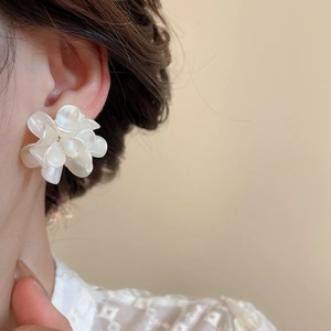 Dettaglio di eleganti orecchini a fiore bianco con perle indossati da una modella