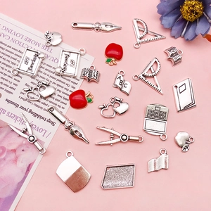 Makroaufnahme verschiedener Lehrer-Themen-Anhänger aus Silber und Rot für DIY-Schmuck