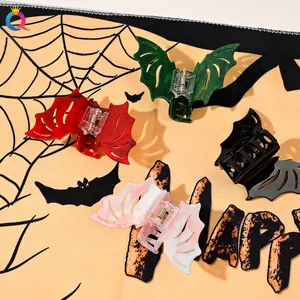 Colorful bat-shaped hair claws in red, green, black and marble on a Halloween background