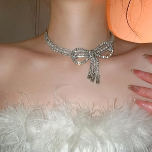 Detail shot of a silver bow necklace with tassels and pearls worn on a female neck