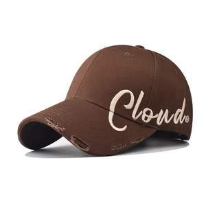 Close-up of white Cloud embroidery and distressed details on brown cotton baseball cap