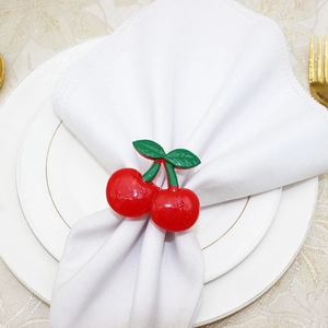 Detailed close-up of cherry napkin ring with glossy red fruits and green leaf accents