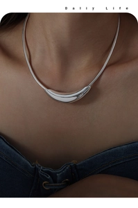 Modern silver snake chain necklace featuring a minimalist curved crescent pendant on a model
