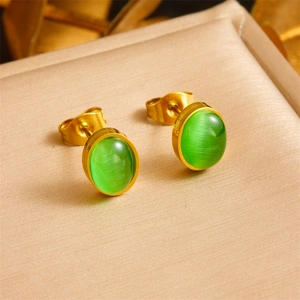 Vintage style gold earrings with green oval chalcedony set on a beige jewelry display stand